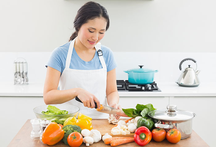 Woman chopping vegetables on her kitchen counter.