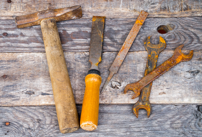 Old rusty vintage tools lying on a weathered table.