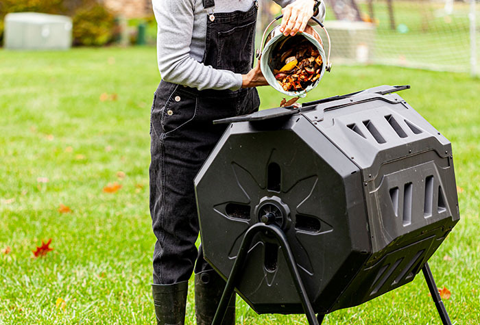 Person adding plant matter to their compost bin.