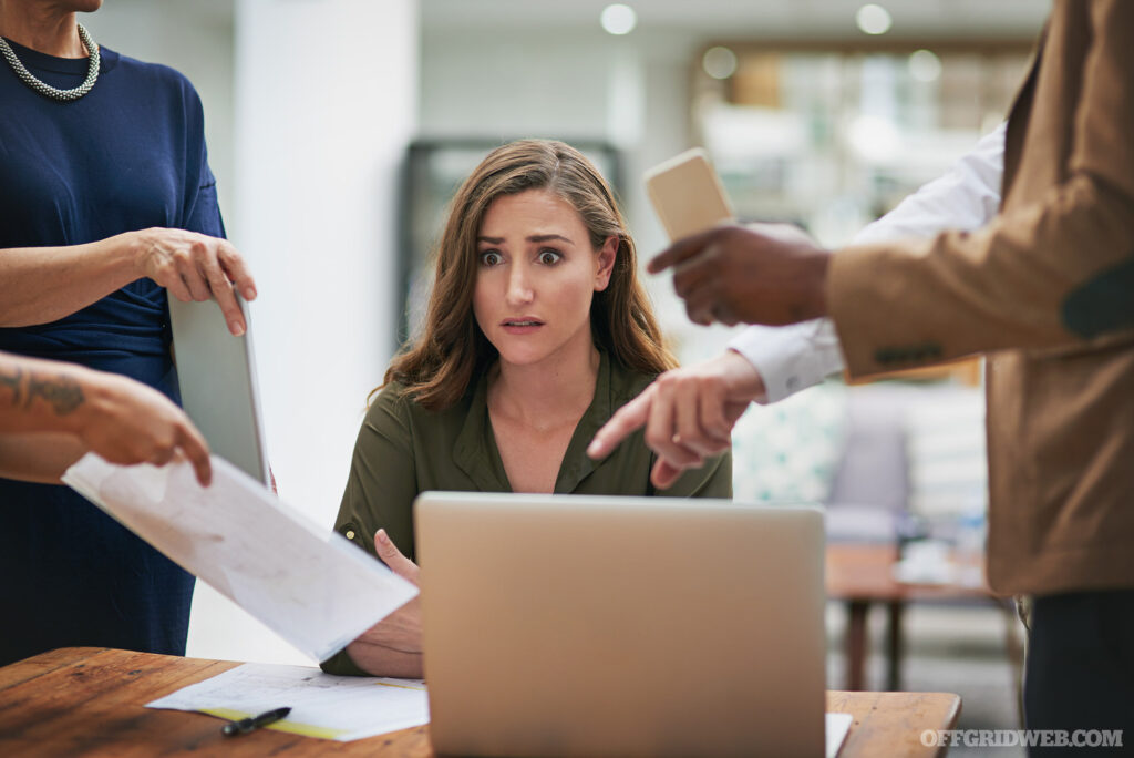 Photo of a young business woman looking anxious while trying to be cool in a demanding office environment.