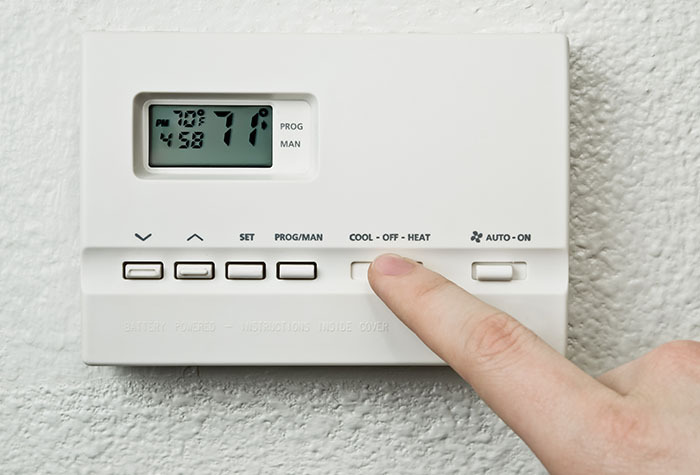 A person changing the temperature on a thermostat.