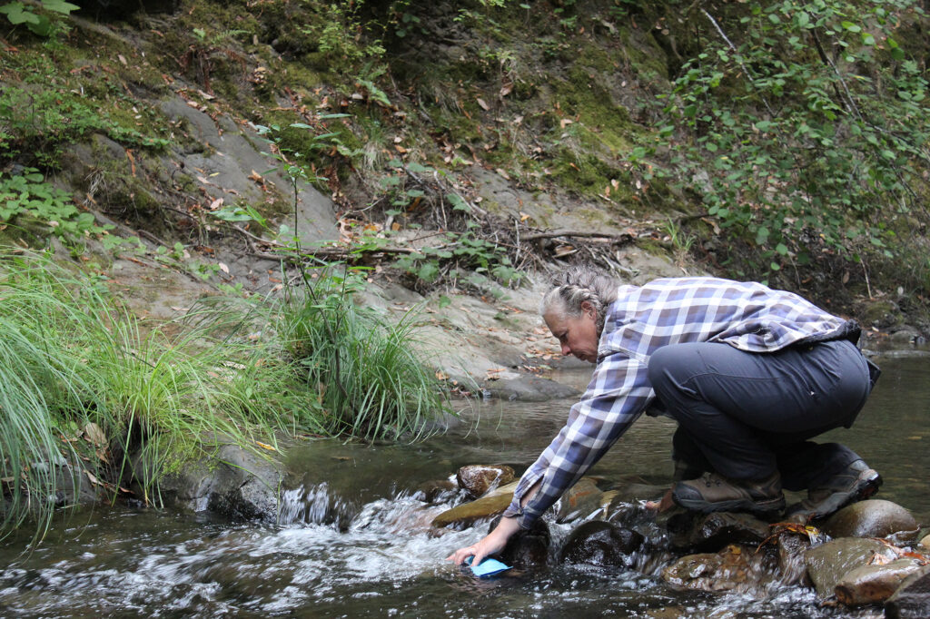 Instructor Amy filling water from a swift moving stream.