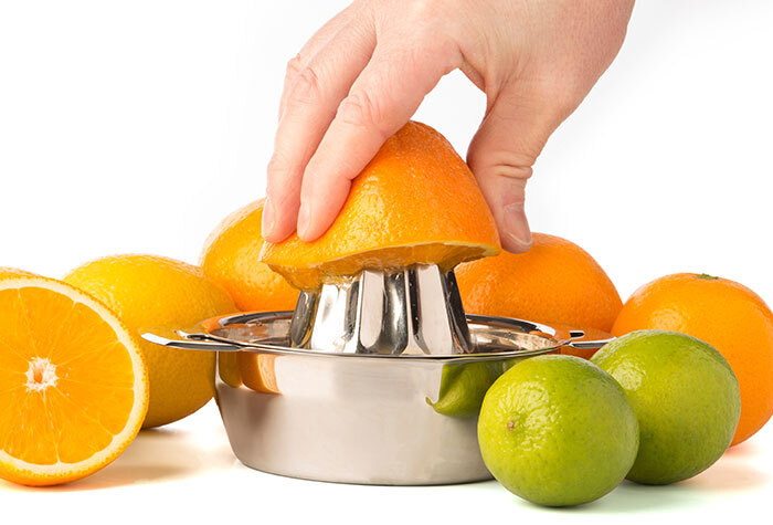 Someone juicing an orange with a hand juicer.