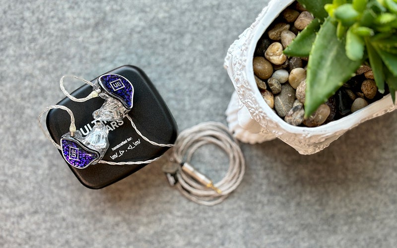 Amethyst and silver UE branded Premier custom molded in-ear monitors for performers on top of a black Ultimate Ears carrying case