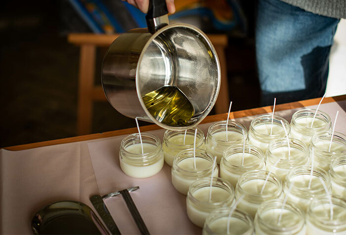 A person pouring wax into jars to make their own candles.