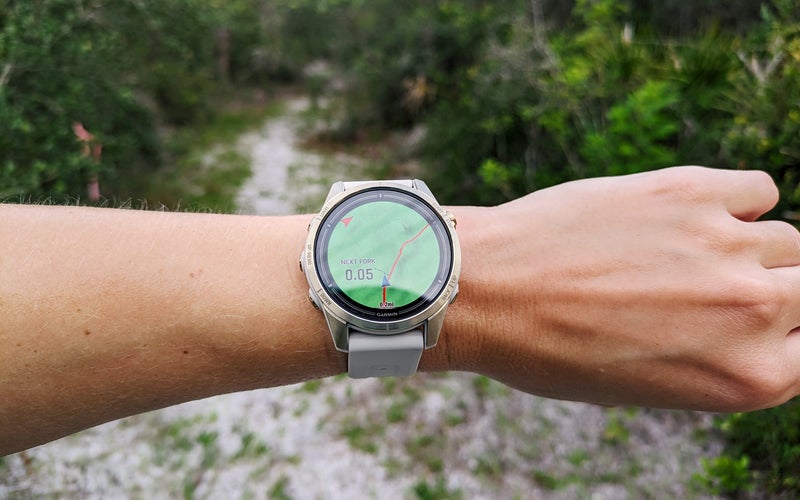 Garmin epix 2 Pro on a wrist in front of a trail through a forest