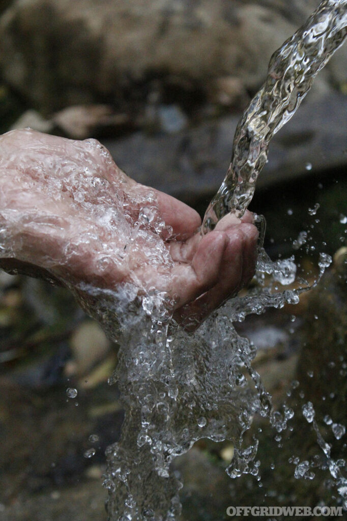 Photo of water pouring over an adult human hand.