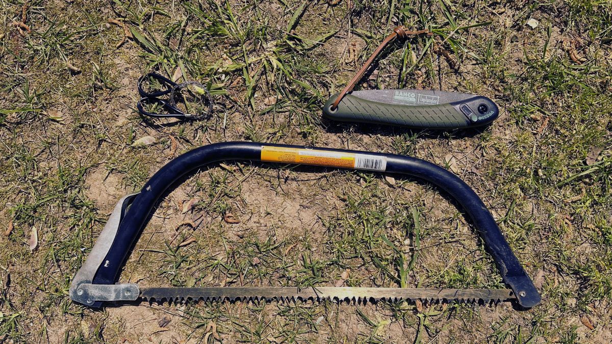 Bow saw, folding saw, and wire saw size comparison on the ground.