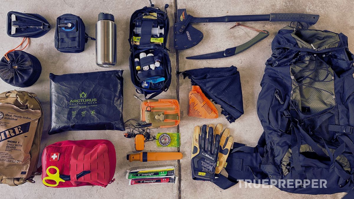 Essential bug out bag items laid out on a concrete floor.