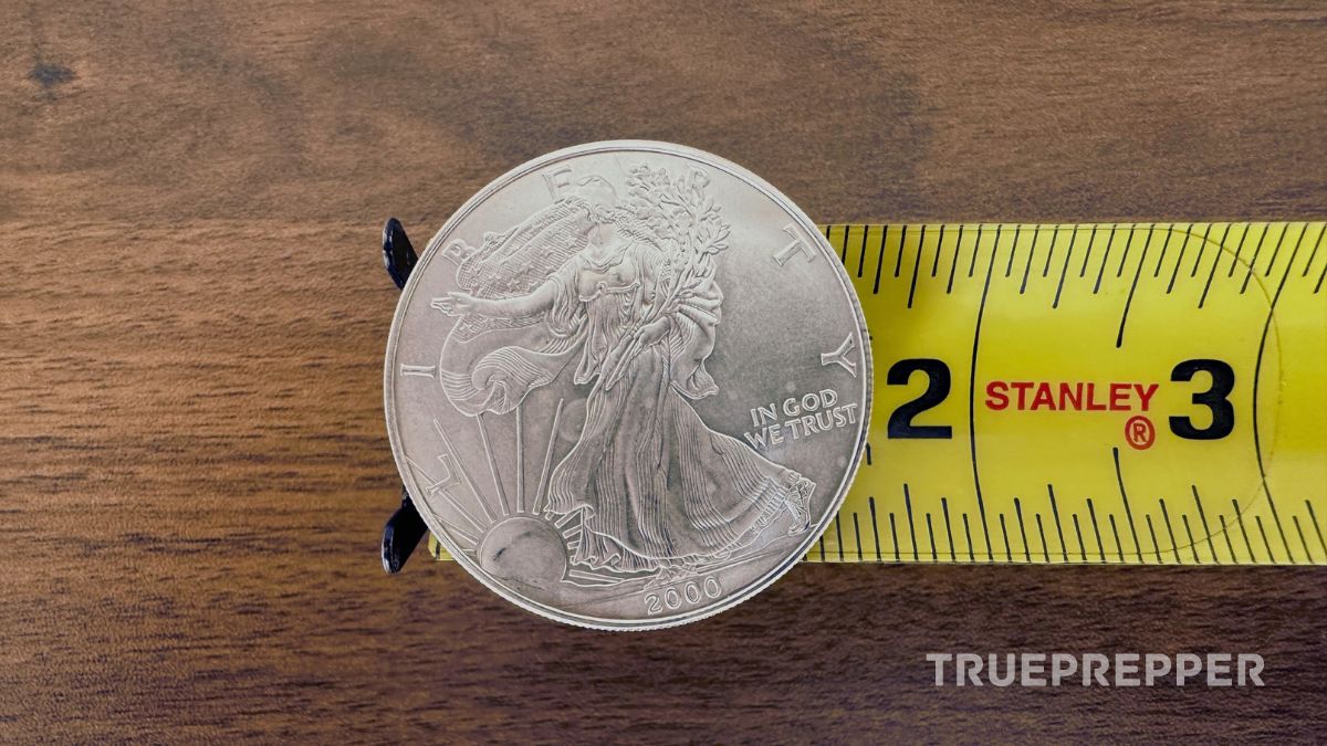 Silver American Eagle coin sitting on top of tape measure to show small size.